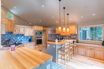 a kitchen with wooden cabinets and a island with bar stools at 585 Knotty Pine - Gorgoeous Moutain Home in Incline Village