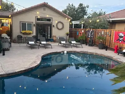 a swimming pool in a yard with chairs and a house at California Cottage in Tracy