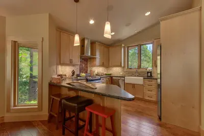 a kitchen with a counter and stools in it at Fairway Favorite - Walk to Tahoe City Shops, Dining & Lake - Pet Friendly in Tahoe City
