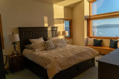 a bedroom with a large bed and a large window at Sierra Lake View at Rubicon by Tahoe Getaways - 3 BR, Panoramic Lake Views, Private Hot Tub & Private beach! in Tahoma