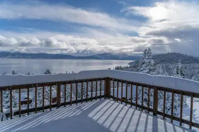 a snow covered balcony with a view of a lake at Sierra Lake View at Rubicon by Tahoe Getaways - 3 BR, Panoramic Lake Views, Private Hot Tub & Private beach! in Tahoma