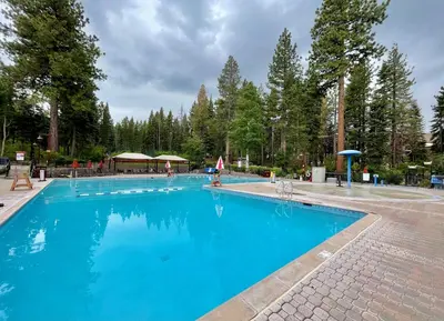a large blue swimming pool with trees in the background at Rocky Point #93 3BR Townhome in Northstar - Shuttle to Slopes - HOA Amenities in Truckee