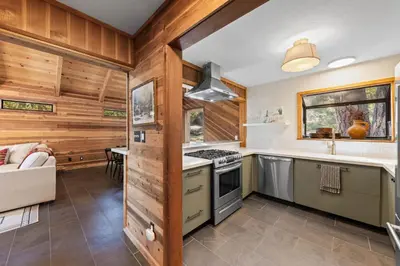 a kitchen with wooden walls and a stove top oven at Sleeping Bear Lodge- Remodeled 3BR Cabin- Fireplace- Ski Shuttle- Pet-Friendly in Truckee