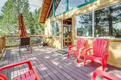a deck with two red chairs and a table at Serene Lakes Cabin with Deck Dog Friendly! in Soda Springs