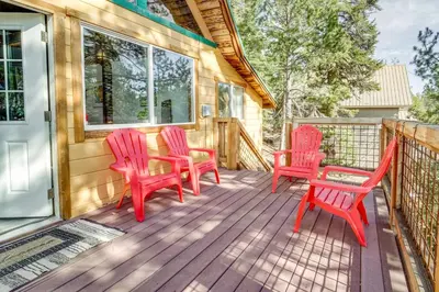 a deck with four red chairs on a house at Serene Lakes Cabin with Deck Dog Friendly! in Soda Springs