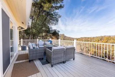 a patio with chairs and a table on a deck at Yosemite Bass Lake VIEWS, 2 Homes, Games, Hot Tub in Coarsegold
