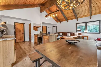 a kitchen and living room with a large wooden table at Stylish 3BR Near Trails w Hot Tub in Tahoe City