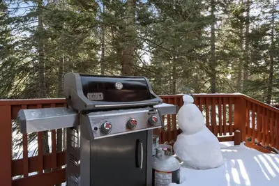 a snowman sitting next to a grill on a deck at Luna Cabin - 5BR Hot Tub A/C Game Room EV Charger in Tahoe Vista