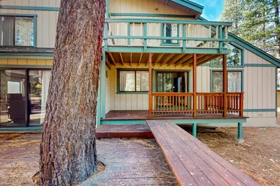 a house with a wooden deck next to a tree at Antler & Pine in South Lake Tahoe