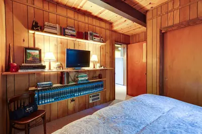 a bedroom with a bed and a tv on a wooden wall at 3 Mi to Big Trees State Park Cabin with Deck in Arnold