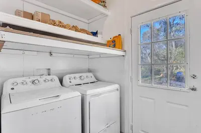 a laundry room with white appliances and a window at Cozy Cabin on 10 acres in Pilot Hill