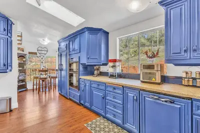 a blue kitchen with blue cabinets and a table at Cozy Cabin on 10 acres in Pilot Hill