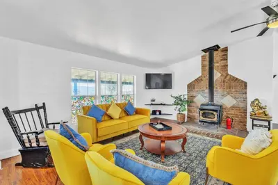 a living room with yellow furniture and a fireplace at Cozy Cabin on 10 acres in Pilot Hill