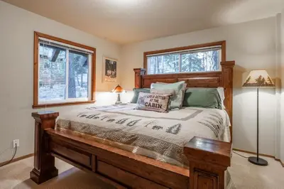 a bedroom with a wooden bed and two windows at North Shore - Pinetree Paradise in Tahoe Vista