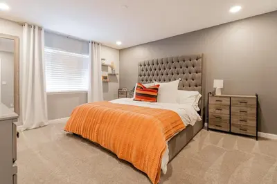 a bedroom with a bed with an orange blanket and a window at Vibrant Boho Home 3 Bed Pet Friendly in Reno