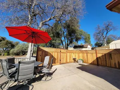 a patio with a table and chairs with a red umbrella at Peaceful Yosemite Retreat-King Suite-Pet Friendly in Oakhurst