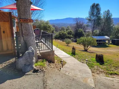 a tree with a sign on it next to a house at Yosemite Gateway Cottage - King Suite - Mountain Views in Oakhurst