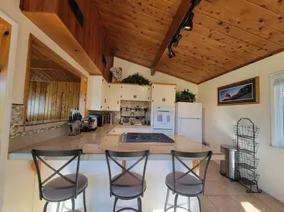 a kitchen with four bar stools and a kitchen with white appliances at Yosemite Gateway Cottage - King Suite - Mountain Views in Oakhurst