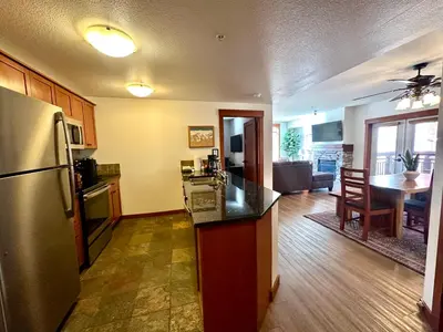 a kitchen and living room with a refrigerator and a table at Quiet, Updated, Corner Condo in the Village! Parking, Pool & Spa in Mammoth Lakes