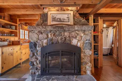 a stone fireplace with a picture on top of it at Coziest Cabin in Tahoe w Stone Fireplace Comfy Beds Close to Slopes & Lake in Carnelian Bay