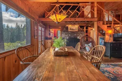 a dining room with a wooden table and a fireplace at Coziest Cabin in Tahoe w Stone Fireplace Comfy Beds Close to Slopes & Lake in Carnelian Bay