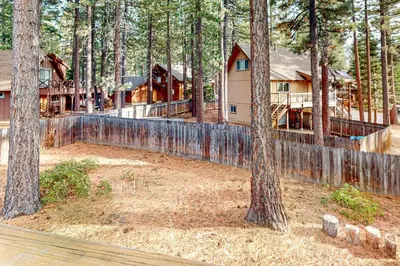 a house in the woods with a fence and trees at High Meadow Hideaway in South Lake Tahoe