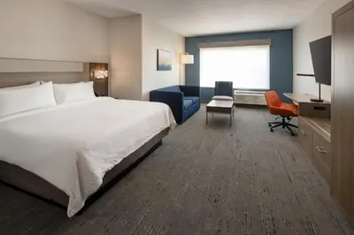 a hotel room with a bed and a desk at Holiday Inn Express & Suites Fresno Airport by IHG in Fresno