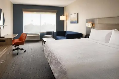 a hotel room with a large bed and a desk at Holiday Inn Express & Suites Fresno Airport by IHG in Fresno