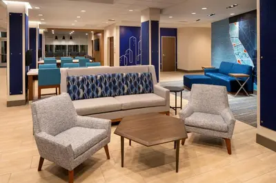 a lobby with a couch and chairs and a bar at Holiday Inn Express & Suites Fresno Airport by IHG in Fresno