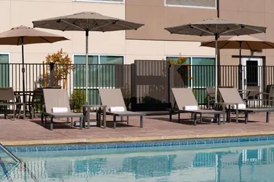 a group of chairs and umbrellas next to a pool at Holiday Inn Express & Suites Fresno Airport by IHG in Fresno