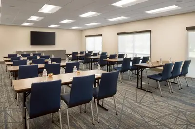 a conference room with tables and chairs and a screen at Holiday Inn Express & Suites Fresno Airport by IHG in Fresno