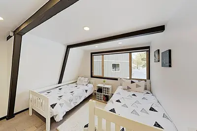 two beds in a room with a window at Modern Gambrel Cabin Near Ski Resorts in Truckee