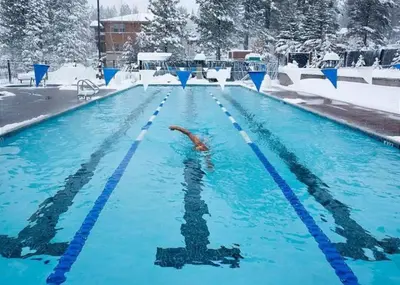 a person swimming in a swimming pool in the snow at Modern Gambrel Cabin Near Ski Resorts in Truckee