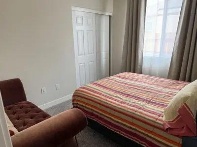 a bedroom with a bed and a chair and a window at Brand New South Sacramento Home in Sacramento