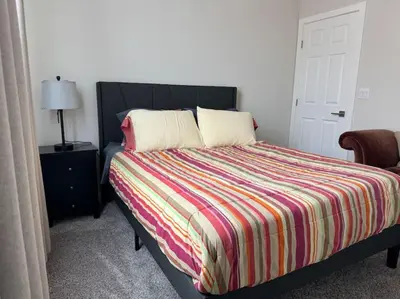 a bedroom with a bed with a colorful striped comforter at Brand New South Sacramento Home in Sacramento
