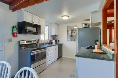 a kitchen with a stainless steel refrigerator and white cabinets at Blue Door Cottage 12 miles to Yosemite Bbq in Oakhurst