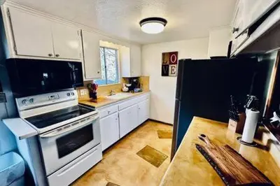 a kitchen with white cabinets and a black refrigerator at Orange Door Electric Fireplace bbq in Oakhurst
