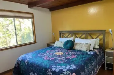a bedroom with a bed with a colorful bedspread and a window at Orange Door Electric Fireplace bbq in Oakhurst