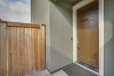 a door to a house with a wooden fence at Newly Built Tracy Home with Backyard and Pool Access! in Tracy