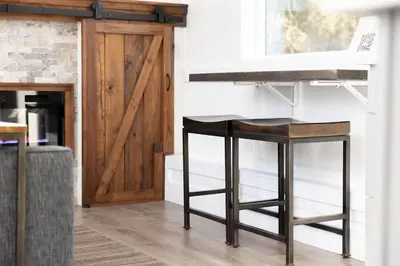 a kitchen with two bar stools and a wooden door at Tiny Home | Lewis Ranch 1 in Lindsay