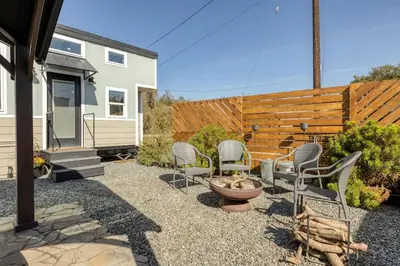 a backyard with chairs and a fire pit and a fence at Tiny Home | Lewis Ranch 1 in Lindsay