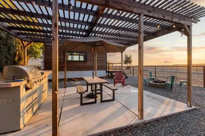 a wooden pergola with a table and a grill at Tiny Cargo Home South in Tulare