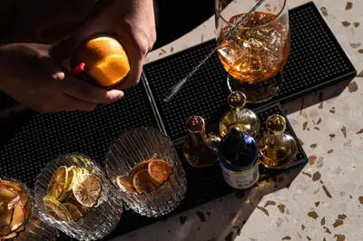 a person holding an orange next to a table with bottles at The Jesse Hotel & Bar in Reno