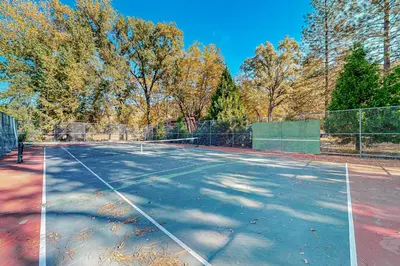 a tennis court with trees in the background at 1BR Dog-Friendly Lakefront Cabin with Canoes in Twain Harte