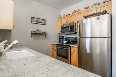 a kitchen with a stainless steel refrigerator and a sink at Juniper Springs Lodge #412 - Luxury Ski in Ski out! 2 Bedroom in Mammoth Lakes