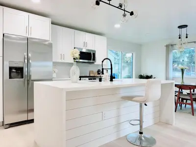 a white kitchen with a refrigerator and a chair at Trendy Trenholm in Elk Grove