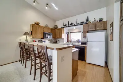 a kitchen with a white refrigerator and wooden cabinets at Mammoth Lakes Condo Walk to Village and Gondola! in Mammoth Lakes