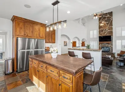 a kitchen with a large island with a stainless steel refrigerator at Luxury 4 Acre Estate - Pickleball, Pool, Hot Tub! in Lockeford