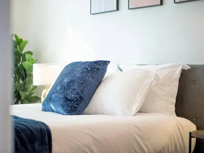 a blue pillow sitting on a bed with white pillows at Luxury 4 Acre Estate - Pickleball, Pool, Hot Tub! in Lockeford