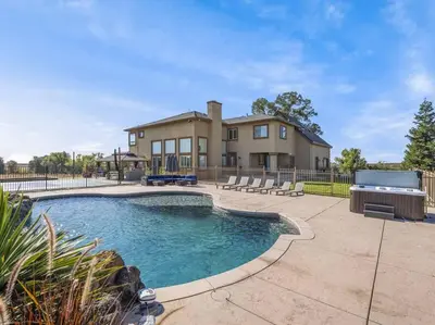a swimming pool in front of a house at Luxury 4 Acre Estate - Pickleball, Pool, Hot Tub! in Lockeford